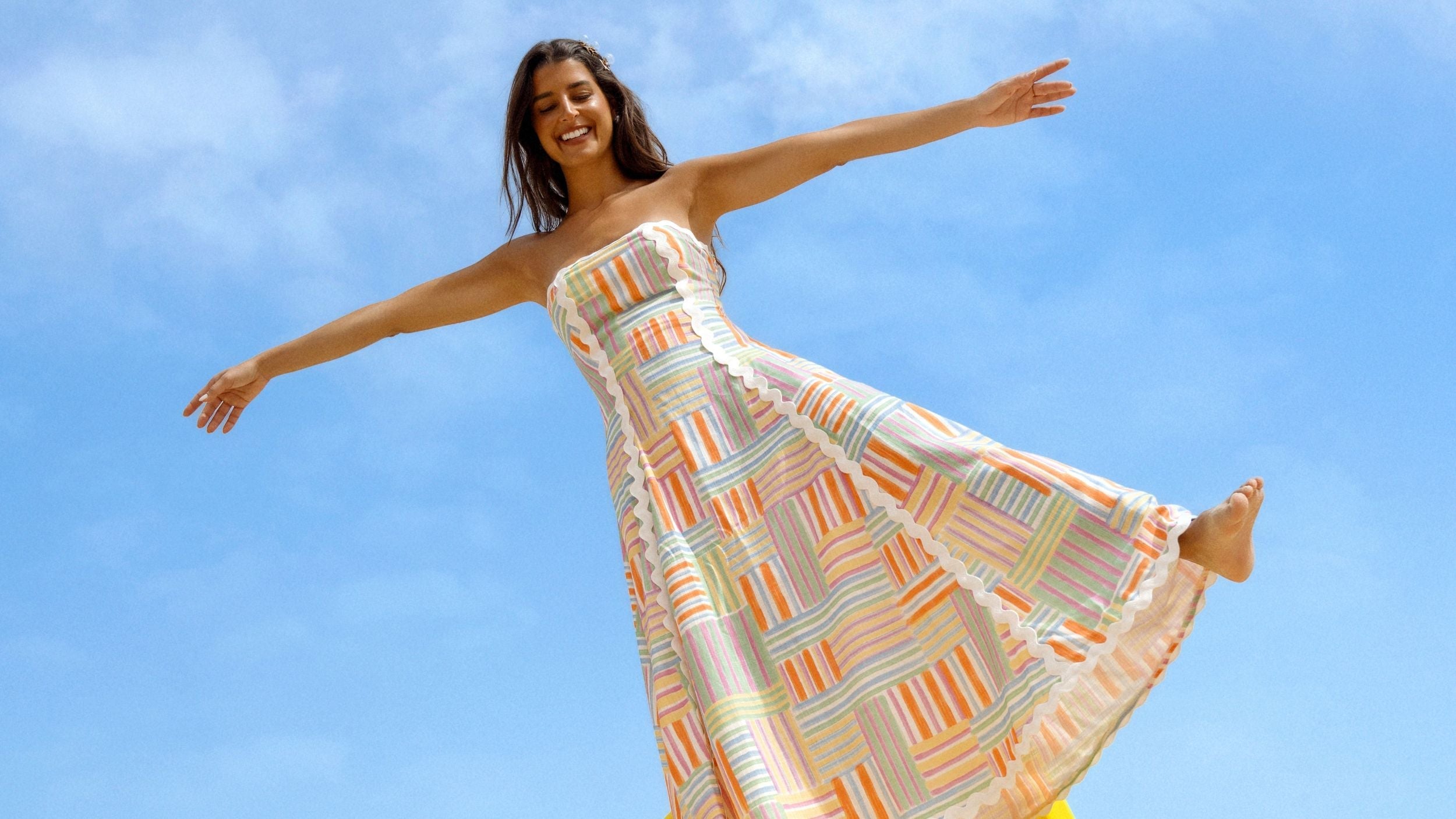 Modelo com vestido colorido e céu de fundo